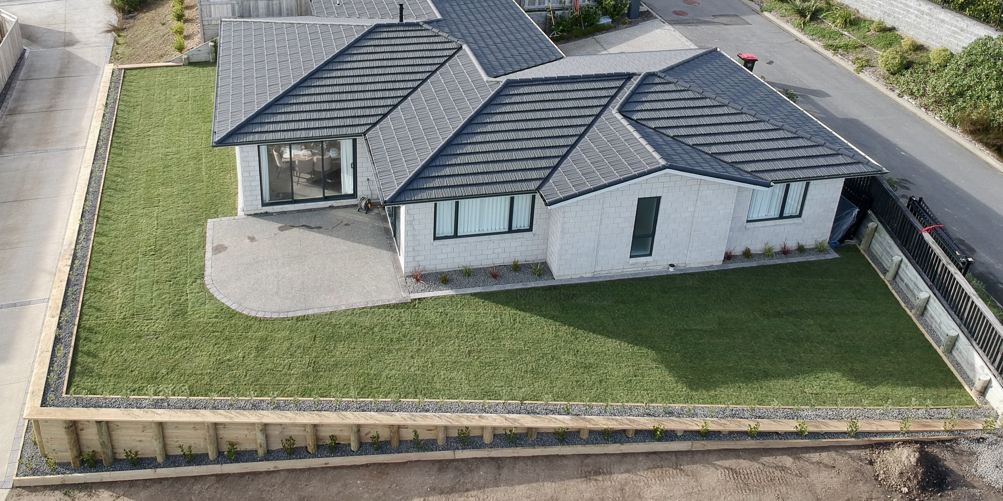 Aerial view of a Wellington home with a timber pole retaining wall enclosing a new ready lawn